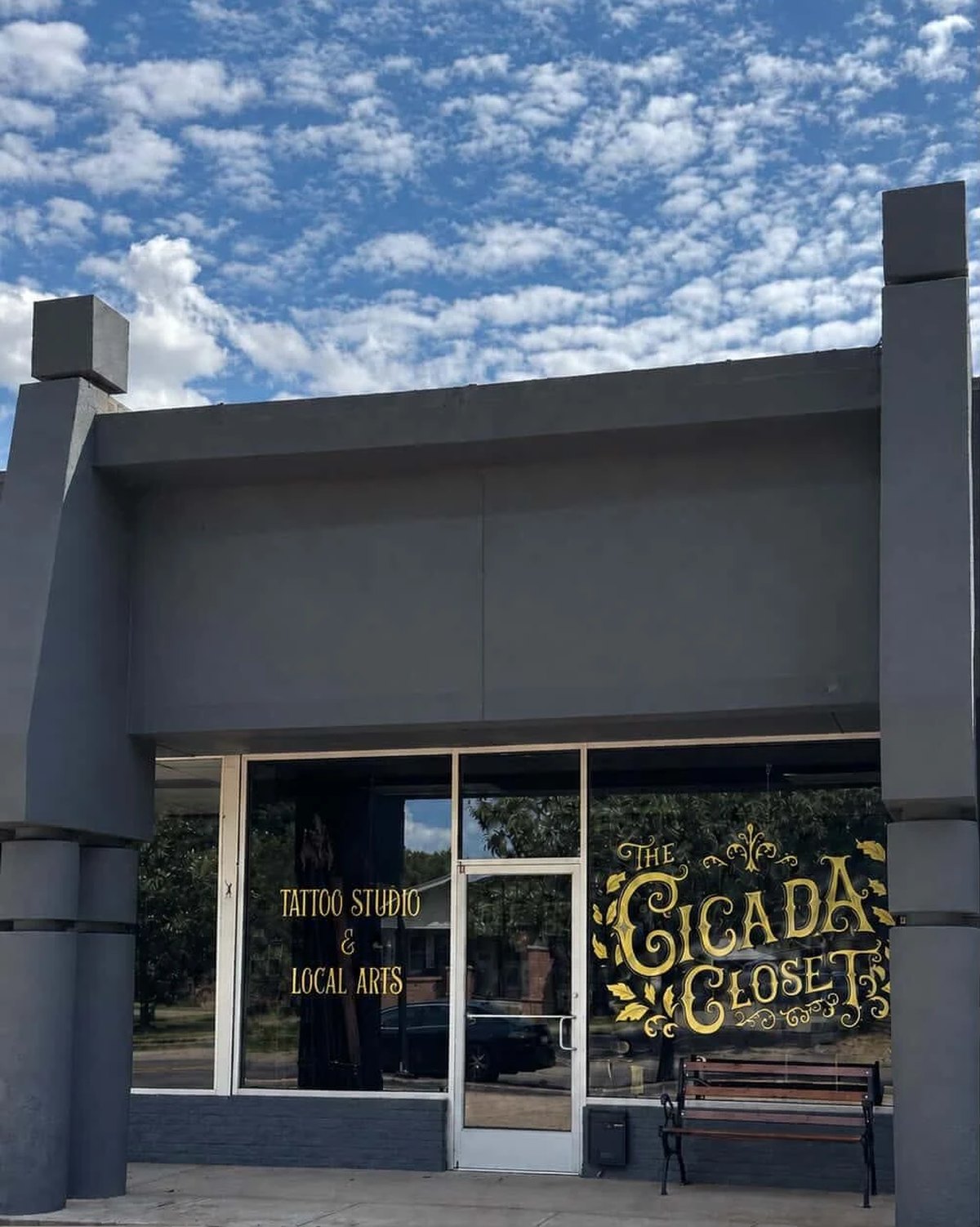 The Cicada Closet from the street: a grey storefront on South Jenkins Avenue with the gold hand-lettered logo on the window and &ldquo;Tattoo Studio & Local Arts&rdquo; lettered beside the door